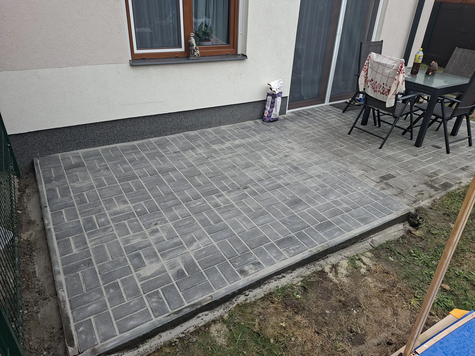 Térkövezett hátsó terasz kerti asztallal és székekkel