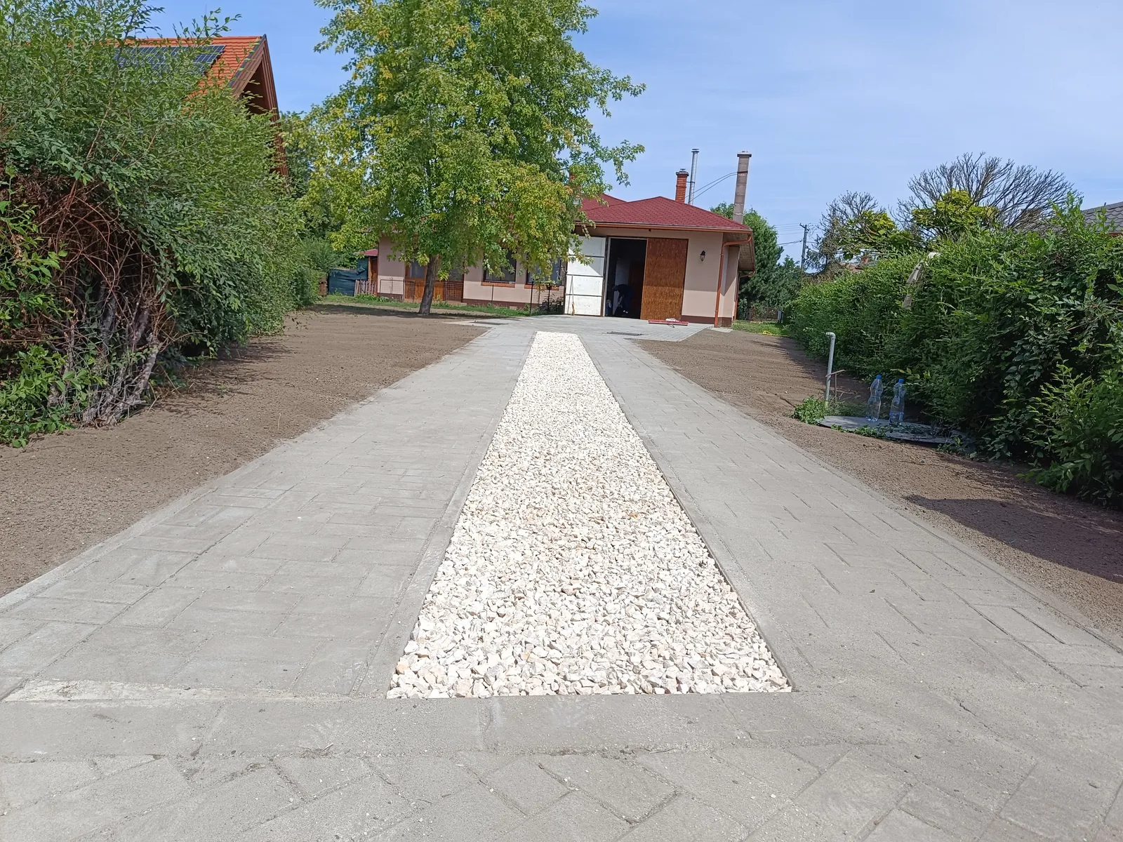 Hosszú térkövezett bejáró fehér kavicscsíkkal