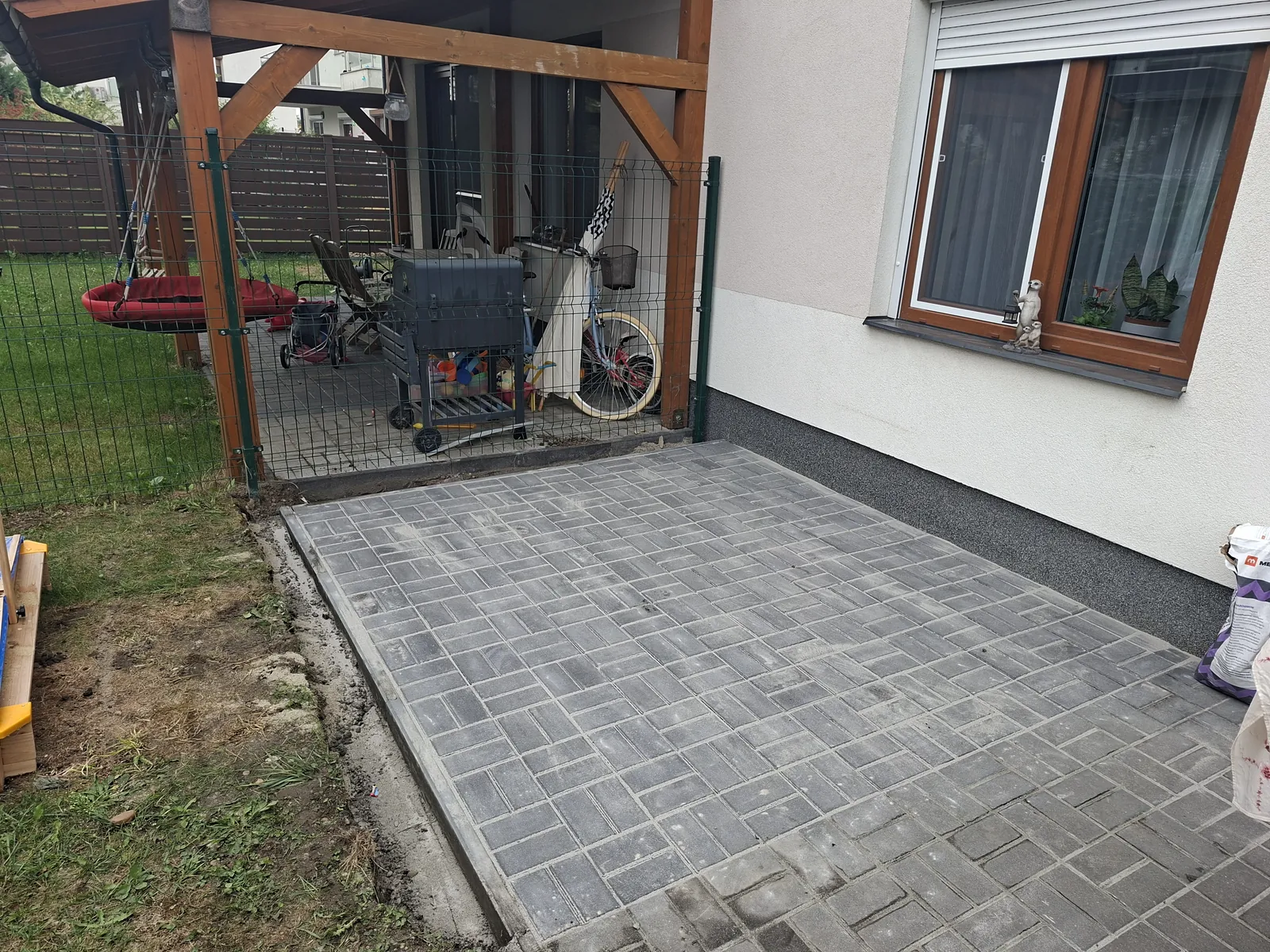 Térkövezett terasz szürke térkővel, fa pergola alatt